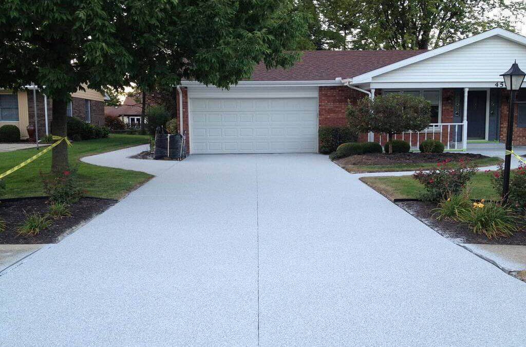 A white and red brick house with a brand new concrete driveway surrounded by yellow and black caution tape so no one walks on it.