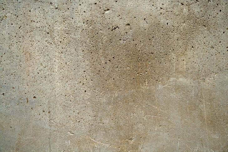 A close-up picture of a concrete wall with some pockets and holes.